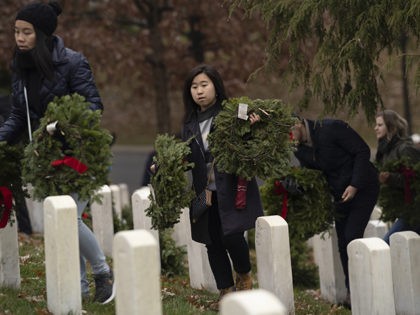 Volunteers arrive to lay holiday wreaths at headstones in Arlington National Cemetery duri