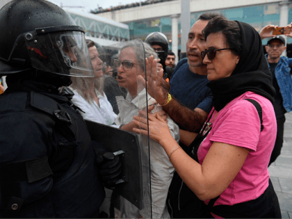 TOPSHOT - Protesters clash with a Spanish policeman outside El Prat airport in Barcelona o